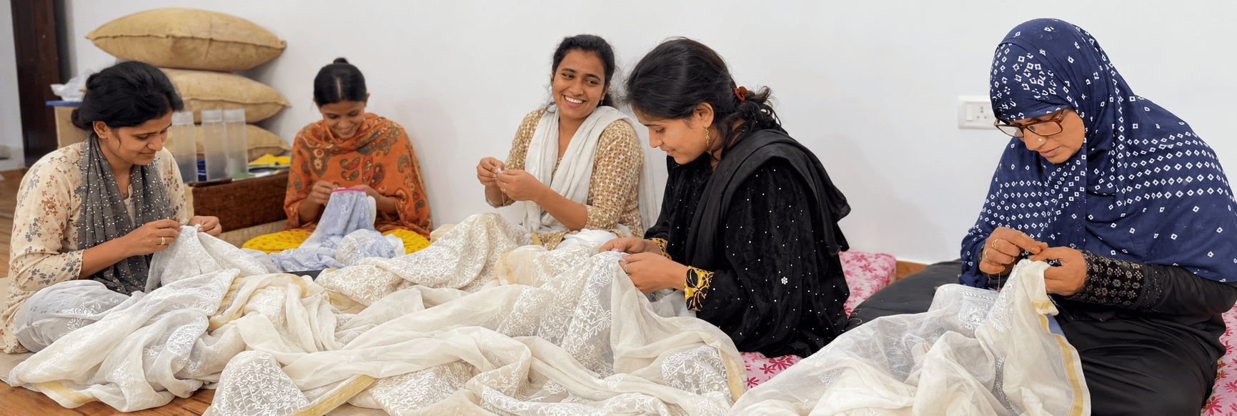 Skilled Chikankari artisans in Lucknow carefully creating traditional hand embroidery using fine needlework and detailed floral motifs on fabric.